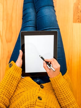 Beautiful woman sitting on the floor working with a tablet