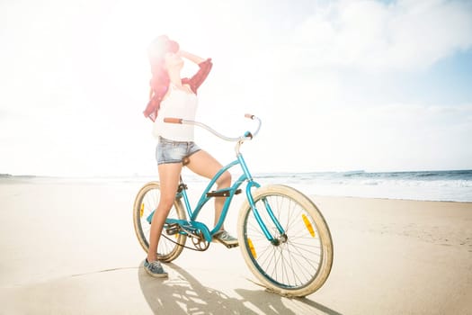 An attractive young woman riding her bicycle on the beach