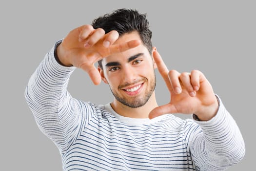 Portrait of happy handsome young man looking through his hands