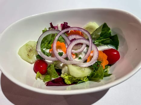 A salad plate with a wide variety of ingredients on a table.