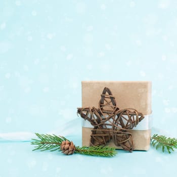 Christmas holiday greeting card with little gift box, pine cones and fir branches, blue background with snow