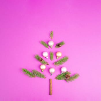 Christmas tree made from fir branches, pink baubles and a cinnamon stick as the trunk, greeting card with copy space