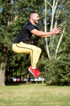 The sporty young guy is jumping on sports training outdoors in the park.