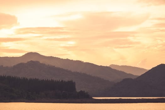 Dramatic scenery of Hazy Layers of Mountain Ranges During Sunrise covered with woods. Colored sunrise in forested mountain slope with fog