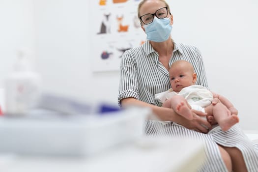 Mother holding her baby boy at medical appointment at pediatrician office