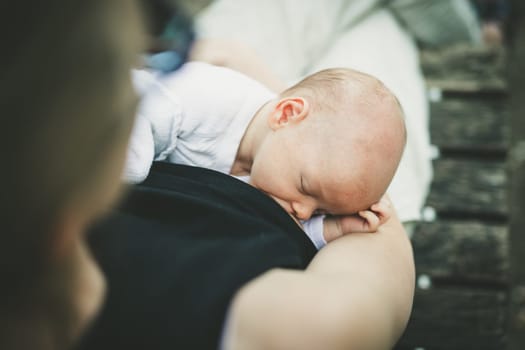 Mother breast feeding and hugging her baby boy outdoors