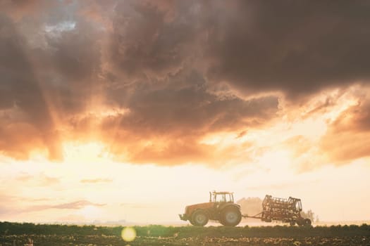 Tractor On Road In Spring Season. Beginning Of Agricultural Spring Season. Cultivator Mounted On Tractor In Countryside Rural Field Landscape. Sunny Spring Sunset Sunrise Sky.