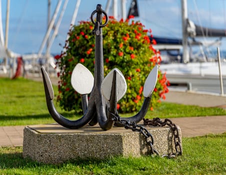 Symbol photo shipping - exhibited old drag anchor in foreground with blurred sailing yachts in background