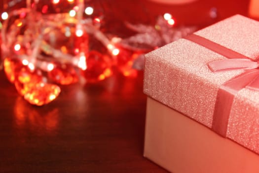 Gift box close-up on the background of a Christmas garland. Concept of christmas, new year. Blurred background, out of focus.