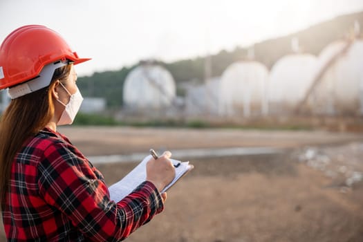 Petroleum Engineers. Happy Asian worker woman in oil chemical industry worker working visual inspection list on clipboard in plant, do Action of worker do safety checklist which is clipped