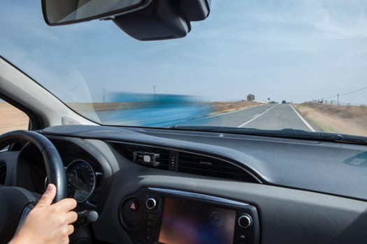 Driver being overtaken by a car in a continuous line and with a gradient change. Motion blurred shot