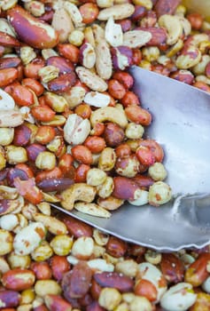 Wooden box with an assortment of fried salty dry fruits. Displayed at street market stall