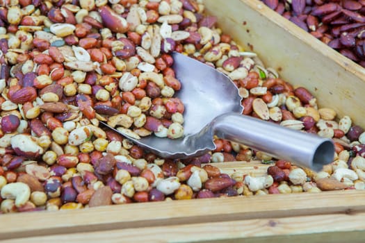 Wooden box with an assortment of fried salty dry fruits. Displayed at street market stall
