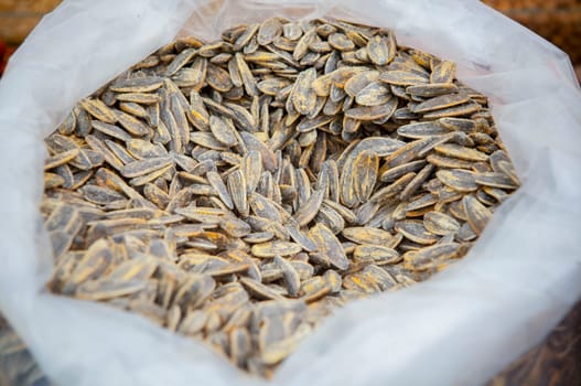 Whole roasted sunflower seeds on rolled up sack. Displayed at street market stall