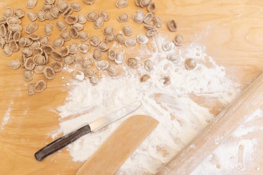 Preparing south italian pasta orecchiette outdoor on the wooden tabletop view. Traditional fresh homemade pasta of apulia region. Mediterranean diet ingredient. Local cousine