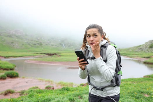 Scared lost hiker checking smart phone in the mountain