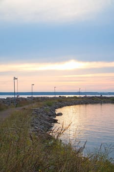 Sunset in Sweden at the harbor of lake Vaettern. Lighthouse in the background at dusk. Landscape shot in Scandinavia.