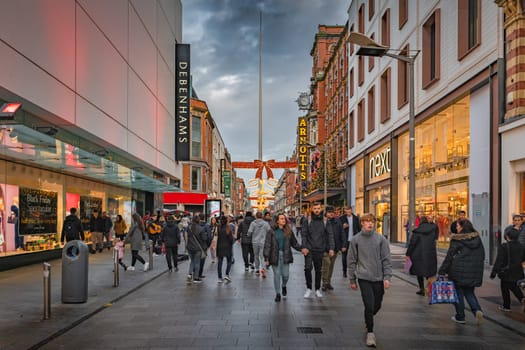 Dublin, November 2019 Henry Street decorated for Christmas with crowds of people enjoying shopping. The Spire on OConnell street visible in background