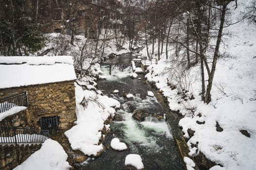 Valira dOrient river in winter with snow banks in El Tarter mountain village in Pyrenees Mountains, Grandvalira, Andorra