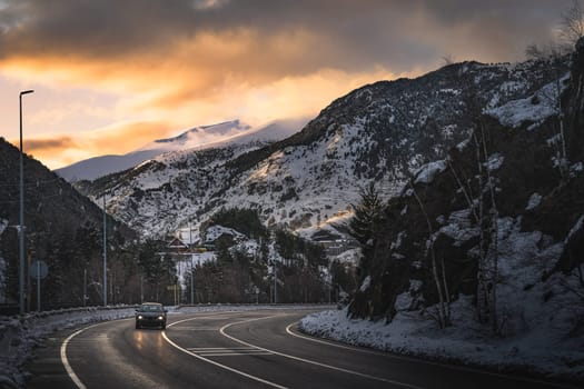Car on the road leading to El Tarter village after dusk. Sunset with sunlight illuminating mountain peaks in Pyrenees mountains, Grandvalira, Andorra