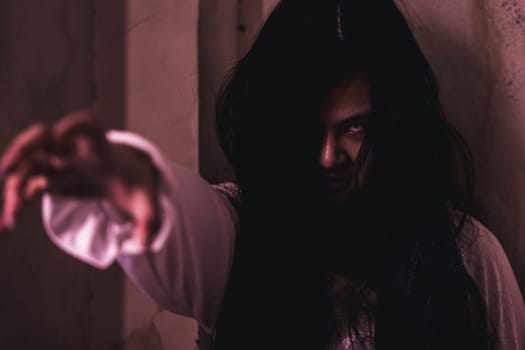 Scary ghost woman. Asian ghost or zombie horror creepy scary have hair covering face and eye reach arm out at abandoned house dark room, female makeup terror zombie face, Happy Halloween day concept