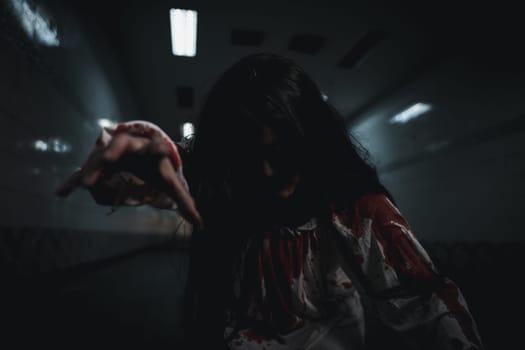 Bloody halloween makeup. Asian woman zombie with blood she death and scary at dark night in tunnel, Horror bloodthirsty ghost girl hair covering face and eye reach arm out, Happy halloween day concept