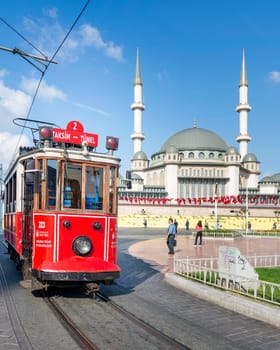 Istanbul, Turkey - September 2 2022: Nostalgic Taksim Tunel Red Tram, or tramvay, with Taksim Mosque in the background, at Taksim Square, Beyoglu district, central Istanbul, in a sunny summer day