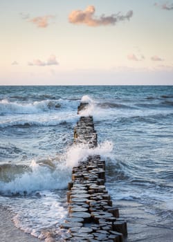 Stormy waves of the Baltic sea under the sun rays in evening. View from the sandy shore
