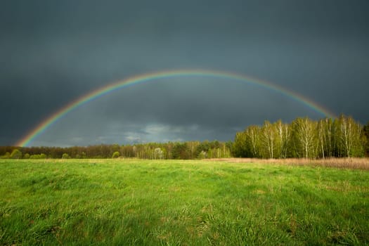 View of a rainbow with a rainy dark cloud, spring day