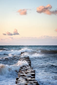 Stormy waves of the Baltic sea under the sun rays in evening. View from the sandy shore