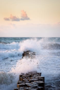 Stormy waves of the Baltic sea under the sun rays in evening. View from the sandy shore