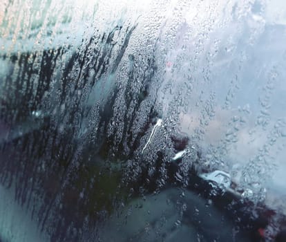 A closeup of car window with drops of morning dew.