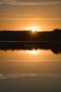 Sunset with reflection on a Swedish lake in Smalland. Romantic evening mood. Landscape shot from Scandinavia in nature