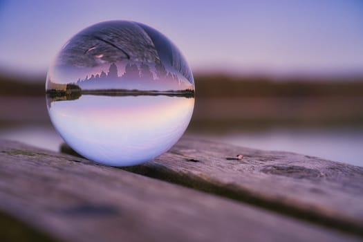 Glass ball on a wooden pier at a Swedish lake at evening hour. Nature shot from Scandinavia