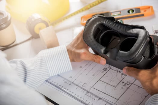 Architectural building design hold back 3D VR glasses and construction plans with blueprints paper project plans, designing man edit building or architecture, technology industry, Architect workplace