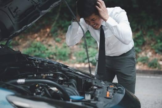 Asian businessman car broken breakdown, angry young stressed man stands trouble car failure problem looking in frustration at failed engine in morning, accident on road outdoor, late for business work