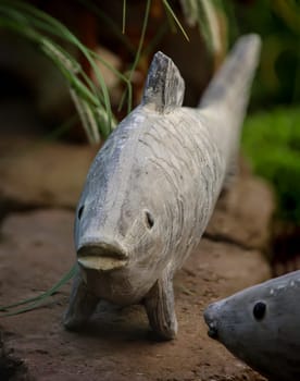 The sculpture, figure of a fish on the edge of a goldfish pond.
