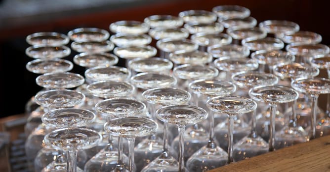Many clean wine glasses are waiting at the counter to be filled.