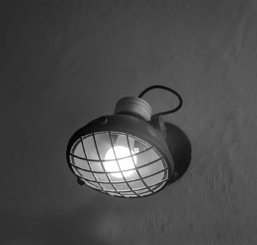 A spotlight-like lamp attached to a house wall.