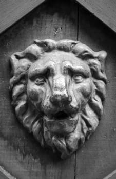A lion head made of wood as a relief on a wooden gate.