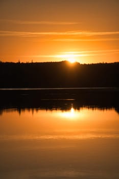 Sunset with reflection on a Swedish lake in Smalland. Romantic evening mood. Landscape shot from Scandinavia in nature