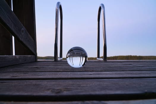Glass ball on a wooden pier at a Swedish lake at evening hour. Nature shot from Scandinavia