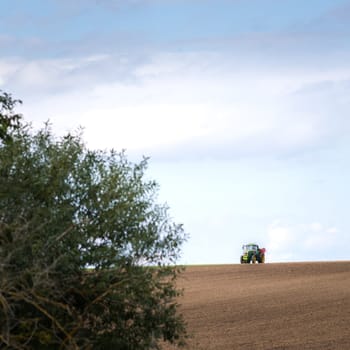 Plowed field by tractor in brown soil on open countryside nature