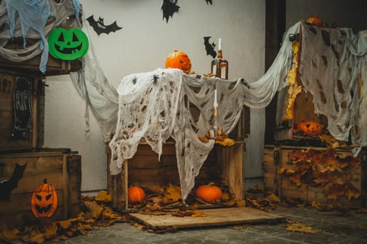 DIY Halloween yard decoration with orange bright halloween pumpkins with carved nose, mouth and eyes and wooden boxes with gauze as web, bats and spiders