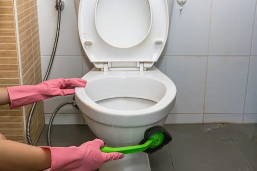 Woman cleaning toilet ware that is very dirty.
