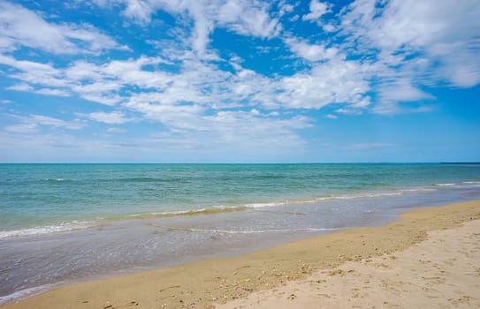Blue cloudy sky and calm blue waters of beautiful Hervey Bay on a sunny day at Pialba on the sandy beach along the shoreline.