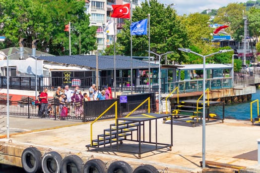 Istanbul, Turkey - August 29, 2022: Bosphorus Strait, Sariyer Ferry Terminal with passengers waiting for ferry, and dense green trees in the background