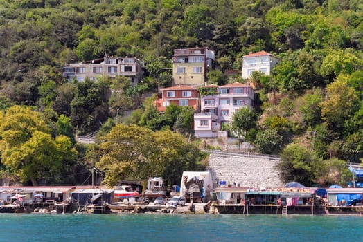 View from the sea of the green mountains of the Europian side of Bosphorus strait, with traditional houses and dense trees in a summer day