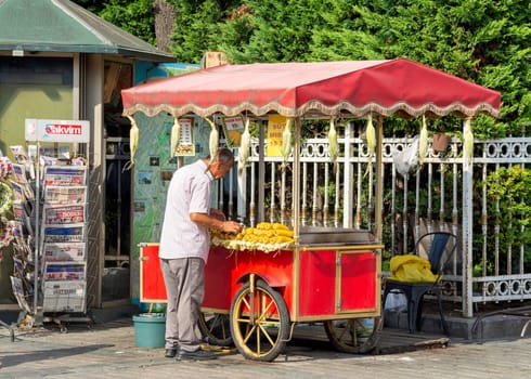 Istanbul, Turkey - August 30, 2022: Middle age man selling corn on traditional Turkish fast food cart at Sultanahmet Square Square