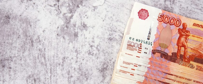 Russian cash banknotes worth five thousand rubles, the bundle lies on a gray background, there is a place for an inscription and text. Layout, mockup.